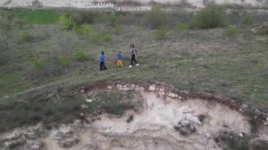 Anne ve iki çocuk bulutlu bir günde vahşi doğada yürüyüş yapıyorlar. Çalılarla ve kayalarla çevrili çimenli bir tepeye çıkıyorlar ve doğal bir çevrede birlikte vakit geçiriyorlar..