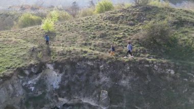 Güneşli bir günde bir anne ve iki çocuk manzaralı bir uçurumun kenarında yürüyüş yaparlar. Manzara engebeli ve vahşi, dramatik kaya oluşumları ve yeşil bahar bitkileriyle.