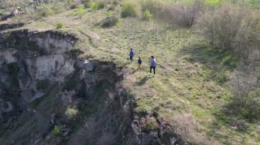 Güneşli bir günde bir anne ve iki çocuk manzaralı bir uçurumun kenarında yürüyüş yaparlar. Manzara engebeli ve vahşi, dramatik kaya oluşumları ve yeşil bahar bitkileriyle.