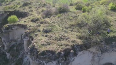 Güneşli bir günde bir anne ve iki çocuk manzaralı bir uçurumun kenarında yürüyüş yaparlar. Manzara engebeli ve vahşi, dramatik kaya oluşumları ve yeşil bahar bitkileriyle.
