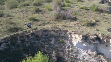 Güneşli bir günde bir anne ve iki çocuk manzaralı bir uçurumun kenarında yürüyüş yaparlar. Manzara engebeli ve vahşi, dramatik kaya oluşumları ve yeşil bahar bitkileriyle.