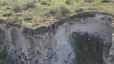 Güneşli bir günde bir anne ve iki çocuk manzaralı bir uçurumun kenarında yürüyüş yaparlar. Manzara engebeli ve vahşi, dramatik kaya oluşumları ve yeşil bahar bitkileriyle.