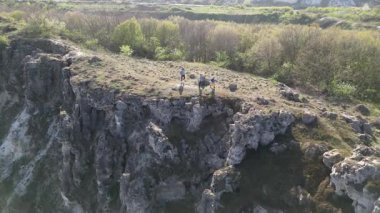 Güneşli bir günde bir anne ve iki çocuk manzaralı bir uçurumun kenarında yürüyüş yaparlar. Manzara engebeli ve vahşi, dramatik kaya oluşumları ve yeşil bahar bitkileriyle.