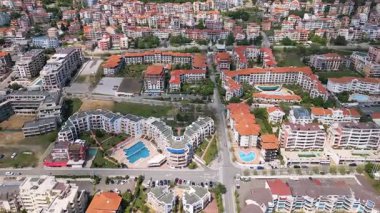 Bulgaristan 'ın Sveti Vlas kentinde kırmızı çatılı konutların ve tatil beldelerinin hava manzarası. Güneşli bir gün, arka planda havuzlar, bahçeler ve dağlar. Karadeniz 'in popüler tatil beldesi.