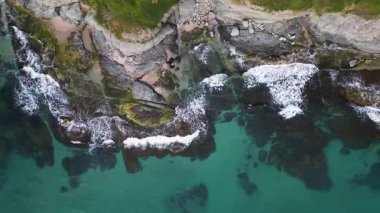 Turkuaz deniz dalgalarının yosun ve berrak suyla kayalık kıyı şeridine düşüşünün havadan aşağı görüntüsü. Bulgaristan kıyıları boyunca vahşi doğa dokusu, dramatik ve manzaralı.