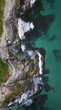 Turkuaz deniz dalgalarının yosun ve berrak suyla kayalık kıyı şeridine düşüşünün havadan aşağı görüntüsü. Bulgaristan kıyıları boyunca vahşi doğa dokusu, dramatik ve manzaralı.