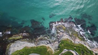 Turkuaz deniz dalgalarının yosun ve berrak suyla kayalık kıyı şeridine düşüşünün havadan aşağı görüntüsü. Bulgaristan kıyıları boyunca vahşi doğa dokusu, dramatik ve manzaralı.