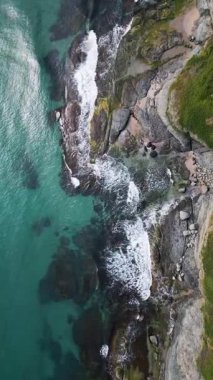 Turkuaz deniz dalgalarının yosun ve berrak suyla kayalık kıyı şeridine düşüşünün havadan aşağı görüntüsü. Bulgaristan kıyıları boyunca vahşi doğa dokusu, dramatik ve manzaralı.