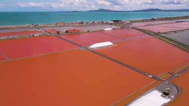 Bulgaristan 'ın Burgaz kenti yakınlarındaki renkli tuz tavalarının hava manzarası. Canlı kırmızı ve turuncu buharlaşma, beyaz tuz yığınları ve turkuaz deniz ile tezat oluşturur. Sanayi ve doğal güzelliğin birleşimi.
