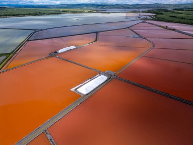 Bulgaristan 'ın Burgaz kenti yakınlarındaki renkli tuz tavalarının hava manzarası. Canlı kırmızı ve turuncu buharlaşma, beyaz tuz yığınları ve turkuaz deniz ile tezat oluşturur. Sanayi ve doğal güzelliğin birleşimi.