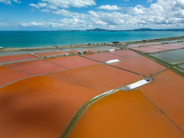 Bulgaristan 'ın Burgaz kenti yakınlarındaki renkli tuz tavalarının hava manzarası. Canlı kırmızı ve turuncu buharlaşma, beyaz tuz yığınları ve turkuaz deniz ile tezat oluşturur. Sanayi ve doğal güzelliğin birleşimi.