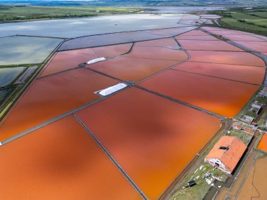 Bulgaristan 'ın Burgaz kenti yakınlarındaki renkli tuz tavalarının hava manzarası. Canlı kırmızı ve turuncu buharlaşma, beyaz tuz yığınları ve turkuaz deniz ile tezat oluşturur. Sanayi ve doğal güzelliğin birleşimi.