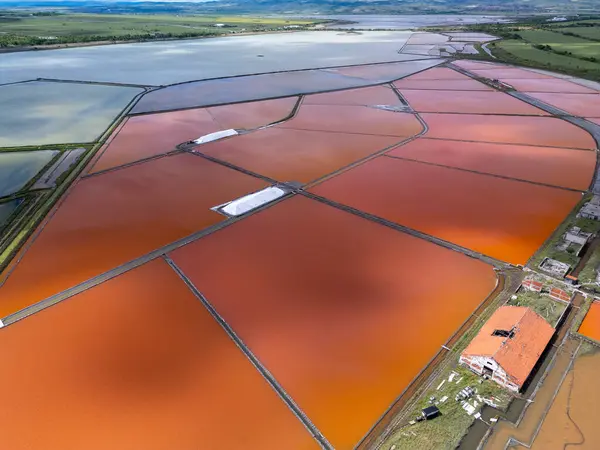 Bulgaristan 'ın Burgaz kenti yakınlarındaki renkli tuz tavalarının hava manzarası. Canlı kırmızı ve turuncu buharlaşma, beyaz tuz yığınları ve turkuaz deniz ile tezat oluşturur. Sanayi ve doğal güzelliğin birleşimi.