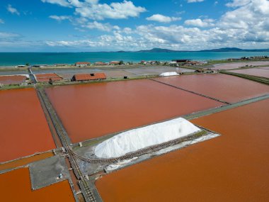 Bulgaristan 'ın Burgaz kenti yakınlarındaki renkli tuz tavalarının hava manzarası. Canlı kırmızı ve turuncu buharlaşma, beyaz tuz yığınları ve turkuaz deniz ile tezat oluşturur. Sanayi ve doğal güzelliğin birleşimi.