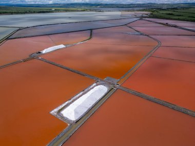 Bulgaristan 'ın Burgaz kenti yakınlarındaki renkli tuz tavalarının hava manzarası. Canlı kırmızı ve turuncu buharlaşma, beyaz tuz yığınları ve turkuaz deniz ile tezat oluşturur. Sanayi ve doğal güzelliğin birleşimi.