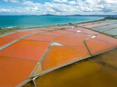 Bulgaristan 'ın Burgaz kenti yakınlarındaki renkli tuz tavalarının hava manzarası. Canlı kırmızı ve turuncu buharlaşma, beyaz tuz yığınları ve turkuaz deniz ile tezat oluşturur. Sanayi ve doğal güzelliğin birleşimi.