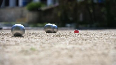Bir petanque oyuncusu, kırmızı Jack Cochonnet 'e yakın bir yerde, oyunda hassasiyet ve kontrol gösteren bir metal topu başarıyla yuvarlar..