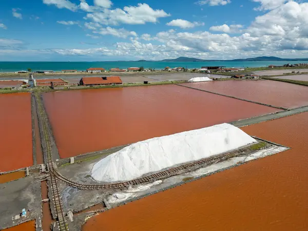 Bulgaristan 'ın Burgaz kenti yakınlarındaki renkli tuz tavalarının hava manzarası. Canlı kırmızı ve turuncu buharlaşma, beyaz tuz yığınları ve turkuaz deniz ile tezat oluşturur. Sanayi ve doğal güzelliğin birleşimi.