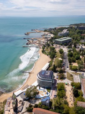 Bulgaristan 'ın Varna kenti yakınlarındaki Saints Constantine ve Helena' daki sahil manzarası. Açık turkuaz deniz, kumlu sahil, tatil köyleri ve güneşli bir günde yemyeşil çevre..