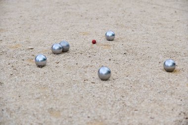Bir oyun sırasında küçük bir hedef topun etrafına dağılmış Petanque topları. Açık hava spor sahnesi, strateji ve hassasiyete odaklı..