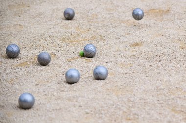 Bir oyun sırasında küçük bir hedef topun etrafına dağılmış Petanque topları. Açık hava spor sahnesi, strateji ve hassasiyete odaklı..