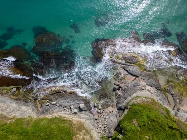 Turkuaz deniz dalgalarının yosun ve berrak suyla kayalık kıyı şeridine düşüşünün havadan aşağı görüntüsü. Bulgaristan kıyıları boyunca vahşi doğa dokusu, dramatik ve manzaralı.