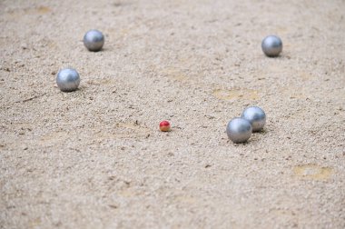Bir oyun sırasında küçük bir hedef topun etrafına dağılmış Petanque topları. Açık hava spor sahnesi, strateji ve hassasiyete odaklı..