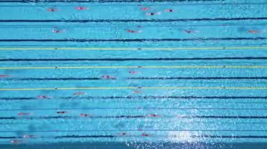 Açık havada olimpiyat boyutunda bir yüzme havuzunun havadan görünüşü ve şeritlerde birden fazla yüzücü eğitimi. Gündüz İHA 'dan yakalanmış. Spor, spor, spor ve eğlence teması için ideal..