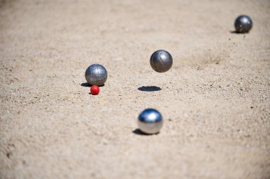 Bir oyun sırasında küçük bir hedef topun etrafına dağılmış Petanque topları. Açık hava spor sahnesi, strateji ve hassasiyete odaklı..