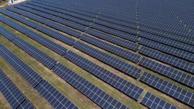 Açık araziye dizilmiş fotovoltaik panelleri olan ve temiz bir gökyüzü altında temiz yenilenebilir enerji üreten büyük bir güneş enerjisi santralinin havadan görüntüsü..