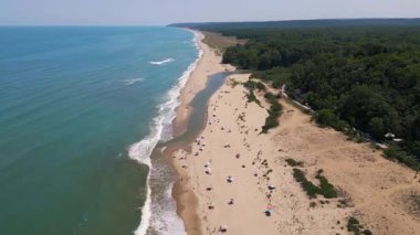 Bulgaristan 'ın Karadeniz kıyısında, güneş banyosu, şemsiye, dalga ve yaz aylarında yemyeşil ormanlarla Kamchia Nehri ağzı ve kumlu plajın havadan görünüşü.