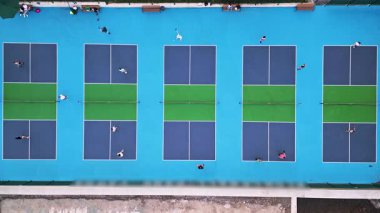 Çoklu Pickleball sahalarının havadan görünüşü, oyuncular iş başında. Güneşli bir günde renkli mavi ve yeşil spor kompleksi. Eğlence aktivitesi ve sağlıklı yaşam tarzı konsepti.