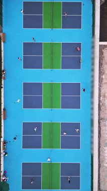 Çoklu Pickleball sahalarının havadan görünüşü, oyuncular iş başında. Güneşli bir günde renkli mavi ve yeşil spor kompleksi. Eğlence aktivitesi ve sağlıklı yaşam tarzı konsepti.