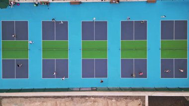 Çoklu Pickleball sahalarının havadan görünüşü, oyuncular iş başında. Güneşli bir günde renkli mavi ve yeşil spor kompleksi. Eğlence aktivitesi ve sağlıklı yaşam tarzı konsepti.