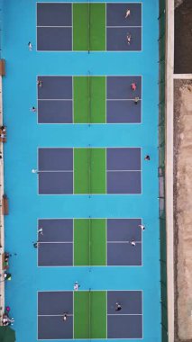 Çoklu Pickleball sahalarının havadan görünüşü, oyuncular iş başında. Güneşli bir günde renkli mavi ve yeşil spor kompleksi. Eğlence aktivitesi ve sağlıklı yaşam tarzı konsepti.
