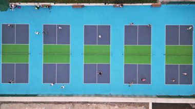 Çoklu Pickleball sahalarının havadan görünüşü, oyuncular iş başında. Güneşli bir günde renkli mavi ve yeşil spor kompleksi. Eğlence aktivitesi ve sağlıklı yaşam tarzı konsepti.