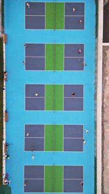 Çoklu Pickleball sahalarının havadan görünüşü, oyuncular iş başında. Güneşli bir günde renkli mavi ve yeşil spor kompleksi. Eğlence aktivitesi ve sağlıklı yaşam tarzı konsepti.
