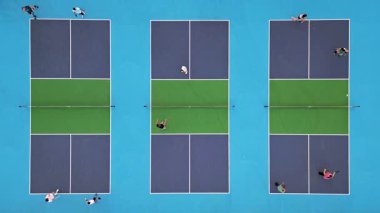 Çoklu Pickleball sahalarının havadan görünüşü, oyuncular iş başında. Güneşli bir günde renkli mavi ve yeşil spor kompleksi. Eğlence aktivitesi ve sağlıklı yaşam tarzı konsepti.