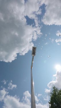 Açık hava duşunun yavaş çekim gücü mavi gökyüzüne ve güneşe su damlacıkları püskürterek parlak bokeh ve yaz atmosferini oluşturur.