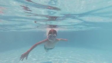 Mutlu çocuk yüzme havuzunda yüzüyor, yaz tatilinin ve güneşin tadını çıkarıyor..