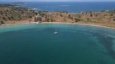Sahil şeridi boyunca turkuaz su, yelkenli ve zeytinlikleri olan huzurlu bir körfezin havadan görünüşü. Idyllic Akdeniz yaz manzarası berrak deniz ve doğal güzellik.