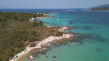 Turkuaz suları, demirli tekneleri ve çam ormanları olan tropikal bir sahil manzarası. Güneşli bir yaz gününde kumlu koyları ve açık mavi denizi olan çarpıcı Akdeniz kıyıları.