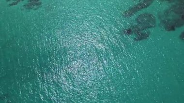 Kristal berraklığında turkuaz deniz suyunun görünür dokuları ve hafif dalgalanmalarla yakın çekim görüntüsü. Tasarım, seyahat ve yaz temalı içerik için mükemmel doğal arkaplan.