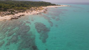 Turkuaz suları ve yoğun ormanı olan kayalık bir Akdeniz sahil şeridinin havadan çekilmiş videosu. İdilik bozulmamış manzara doğa, seyahat ve yaz temalı içerik için mükemmel..