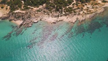 Turkuaz suları ve yoğun ormanı olan kayalık bir Akdeniz sahil şeridinin havadan çekilmiş videosu. İdilik bozulmamış manzara doğa, seyahat ve yaz temalı içerik için mükemmel..