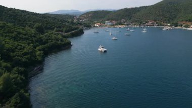 Yeşil tepelerle çevrili bir sahil köyünün yakınındaki tekneleri ve yatları olan huzurlu bir marinanın klibi. Sakin bir yaz gününde Akdeniz limanı manzarası.