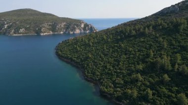 İki yemyeşil yarımada arasında sakin bir deniz kanalından geçen bir teknenin hava görüntüsü. Güneşli bir günde doğaya, suya ve özgürlüğe huzurlu ve manzaralı bir bakış..