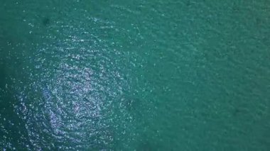 Kristal berraklığında turkuaz deniz suyunun görünür dokuları ve hafif dalgalanmalarla yakın çekim görüntüsü. Tasarım, seyahat ve yaz temalı içerik için mükemmel doğal arkaplan.