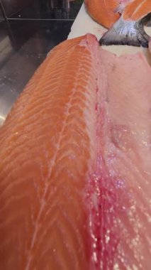 Profesyonel bir mutfakta kesme tahtasında taze çiğ somon filetosu yakın plan. Temiz hazırlık ve pembe balık etinin canlı dokusu.