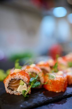 Tobiko, krema sosu ve mikroyeşilliklerle kaplı lezzetli suşi dürümleri Japon restoranındaki siyah bir tabağa dizilmişti..